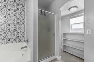 Bathroom featuring a stall shower, a bath, and tile patterned floors