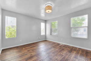 Empty room featuring a textured ceiling, plenty of natural light, and dark wood-style floors
