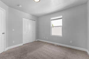Unfurnished bedroom featuring carpet, a textured ceiling, and a closet