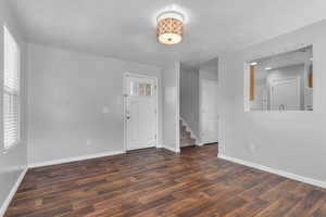 Spare room featuring dark wood-style flooring, stairs, and a textured ceiling