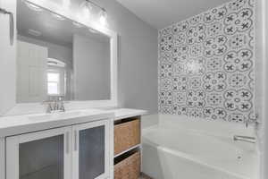 Bathroom featuring vanity, a bath, and a textured ceiling