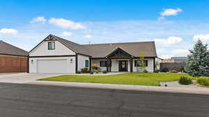 Modern inspired farmhouse featuring covered porch, a garage, driveway, and board and batten siding