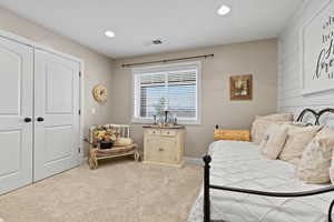 Bedroom featuring light carpet, recessed lighting, and a closet
