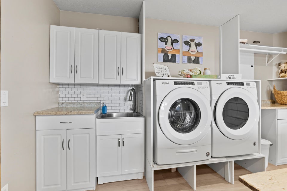 Laundry room with washing machine and dryer, cabinet space, and light wood-type flooring