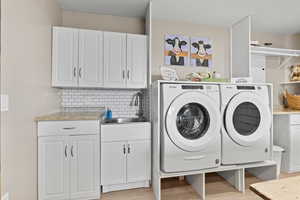 Laundry room with washing machine and dryer, cabinet space, and light wood-type flooring