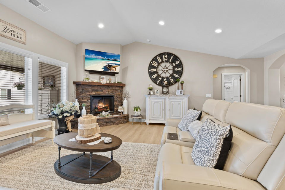 Living room with recessed lighting, light wood finished floors, a fireplace, lofted ceiling, and arched walkways