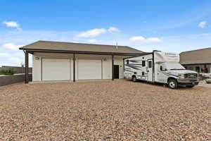 Ranch-style house with a garage, a shingled roof, and an outbuilding