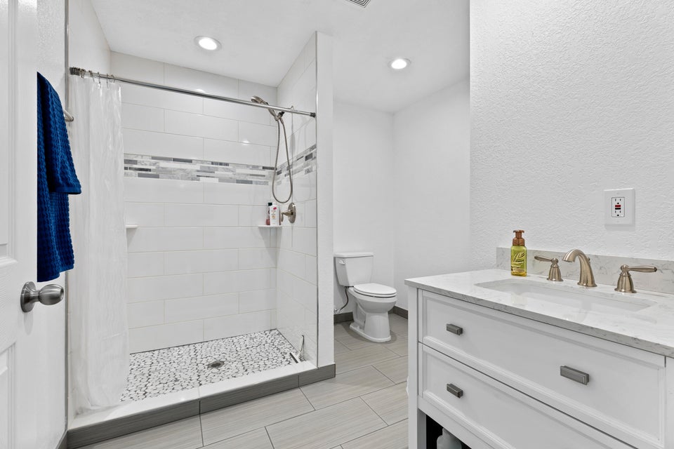 Full bath with vanity, a stall shower, a textured wall, and recessed lighting
