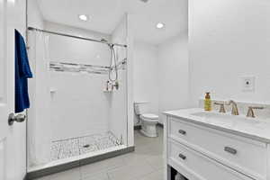 Full bath with vanity, a stall shower, a textured wall, and recessed lighting