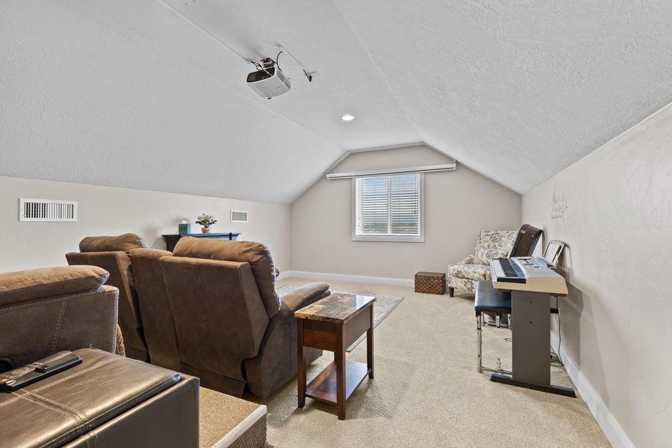 Cinema room featuring light carpet, vaulted ceiling, and a textured ceiling