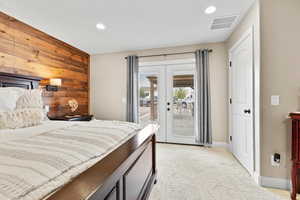 Bedroom featuring french doors, wooden walls, access to outside, light colored carpet, and recessed lighting