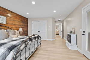 Bedroom featuring wood walls, recessed lighting, light wood-style flooring, and a closet