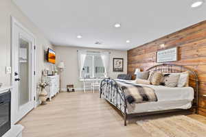 Bedroom featuring wood walls, light wood-style floors, and recessed lighting