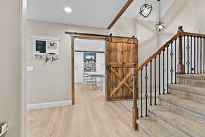 Entryway with light wood-style flooring, recessed lighting, a barn door, a textured ceiling, and stairs