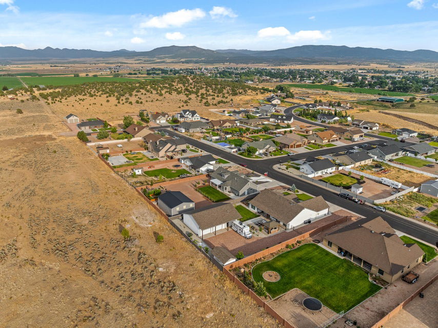 Aerial view of property and surrounding area featuring a mountainous background and nearby suburban area
