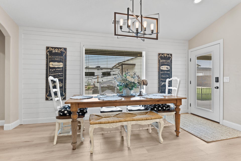 Dining space with light wood-style floors, wooden walls, plenty of natural light, and vaulted ceiling