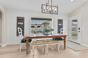 Dining space with light wood-style floors, wooden walls, plenty of natural light, and vaulted ceiling
