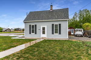 View of front facade with a front yard, a chimney, and roof with shingles