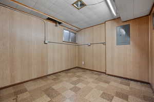 Spare room featuring electric panel and wood walls