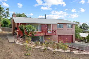 Ranch-style home with a shingled roof, brick siding, a chimney, a garage, and driveway