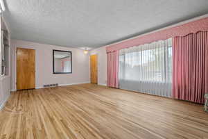 Empty room featuring a textured ceiling, plenty of natural light, and light wood-type flooring