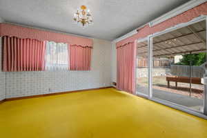 Spare room with wallpapered walls, a chandelier, and a textured ceiling