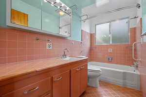 Bathroom featuring shower / bathtub combination, vanity, light tile patterned floors, tile walls, and backsplash