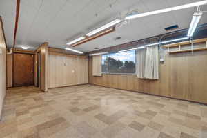 Below grade area featuring light flooring and wood walls