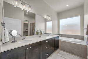 Bathroom with light tile patterned floors, a garden tub, a spacious closet, and recessed lighting