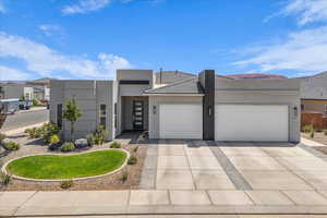View of front of house featuring a garage, driveway, and stucco siding