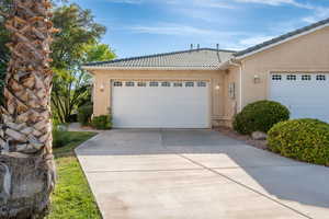 View of front of home featuring a tiled roof, stucco siding, concrete driveway, and an attached garage