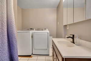 Bathroom with light tile patterned flooring, a textured ceiling, independent washer and dryer, and vanity