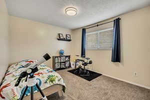 Carpeted bedroom featuring a textured ceiling and baseboards