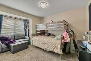 Bedroom with a textured ceiling and carpet flooring