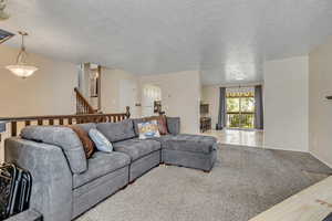 Living room with carpet floors, a textured ceiling, and arched walkways