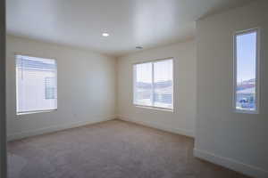 Unfurnished room with plenty of natural light, light colored carpet, and recessed lighting