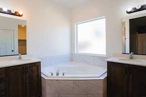 Bathroom with two sinks, vanity, and a bath