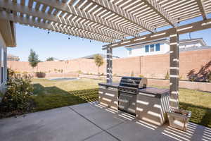 Fenced backyard featuring a pergola, a patio, and exterior kitchen
