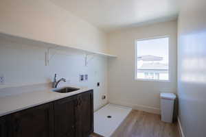 Washroom with washer hookup, light wood finished floors, hookup for an electric dryer, and cabinet space
