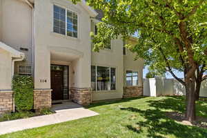 View of front of house with stone siding, a gate, and stucco siding
