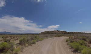 View of dirt / gravel road with a mountain view and a rural view