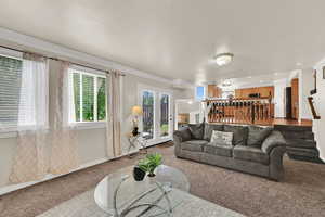 Living area featuring carpet, a textured ceiling, ornamental molding, and stairway