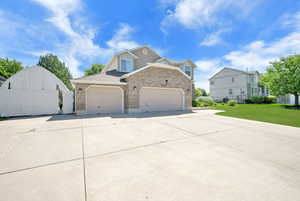 View of side of property with brick siding, driveway, and a gate