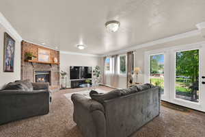 Carpeted living room featuring ornamental molding, a brick fireplace, and a textured ceiling