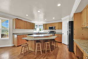 Kitchen featuring light wood-type flooring, ornamental molding, a kitchen bar, a kitchen island, and recessed lighting