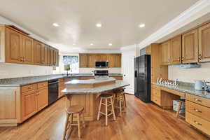 Kitchen featuring crown molding, a kitchen breakfast bar, a center island, recessed lighting, and appliances with stainless steel finishes