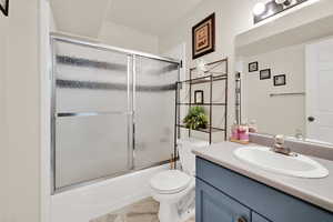 Bathroom featuring vanity and bath / shower combo with glass door