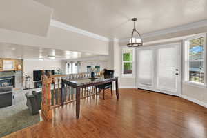 Dining room with crown molding, healthy amount of natural light, a fireplace, wood finished floors, and a textured ceiling
