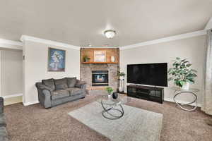 Living area featuring carpet floors, a textured ceiling, crown molding, and a brick fireplace