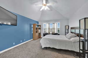 Carpeted bedroom featuring vaulted ceiling and a ceiling fan